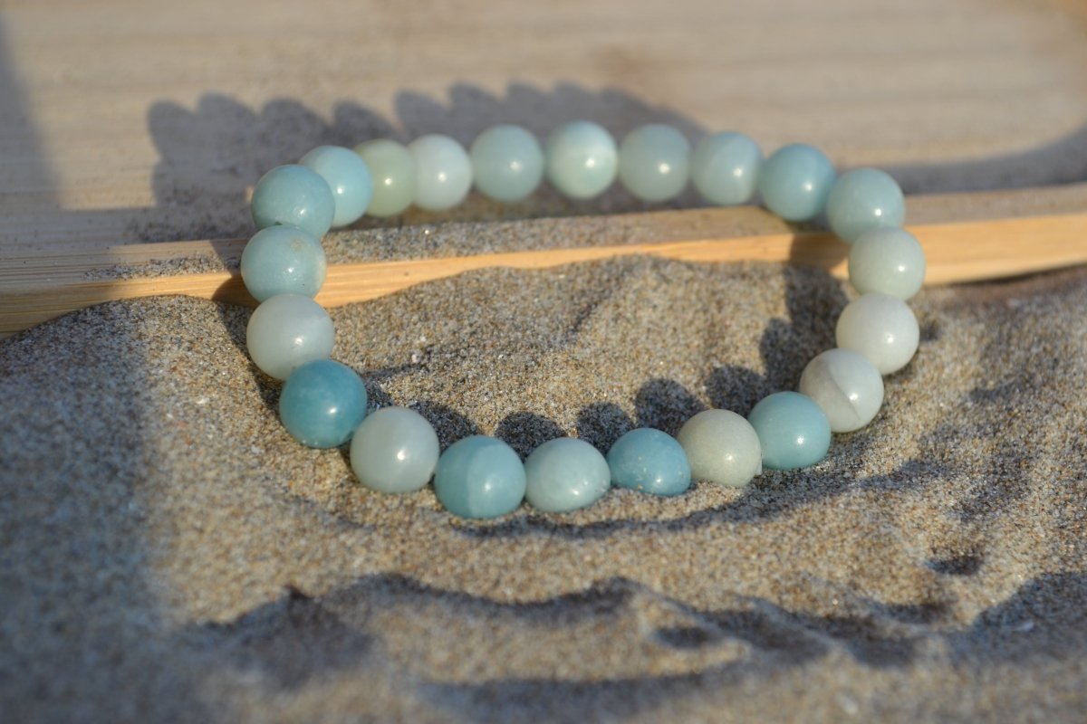 Bracelet Amazonite en pierre naturelle posé sur du sable à cheval sur un plateau en bois. perle de diamètre 7-8mm