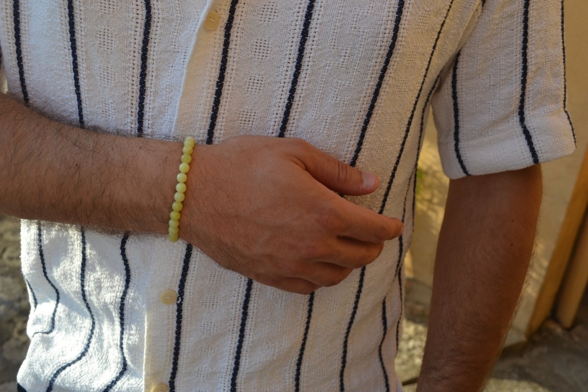 Bracelet Jade Citron en pierre naturelle porté sur un poignet d'un homme au niveau du ventre. perle de diamètre 5-6mm