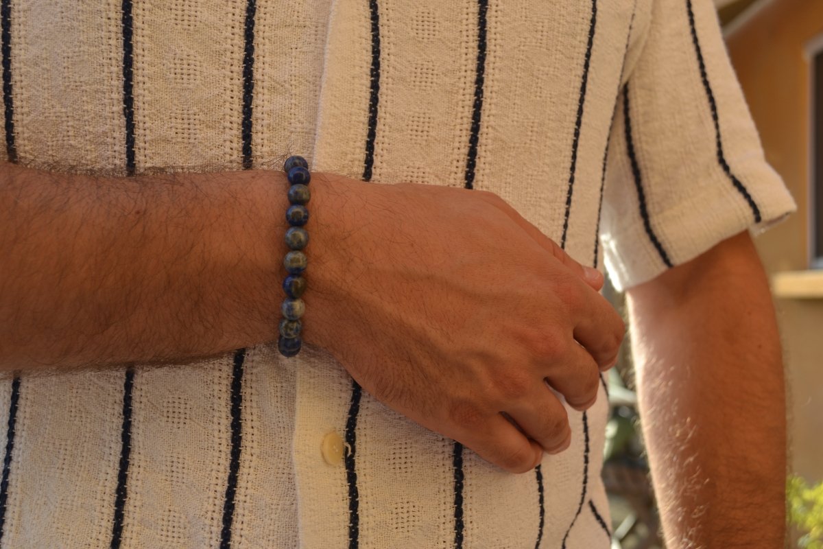 Bracelet Lapis Lazuli en pierre naturelle porté sur un poignet d'un homme au niveau du ventre. perle de diamètre 7-8mm