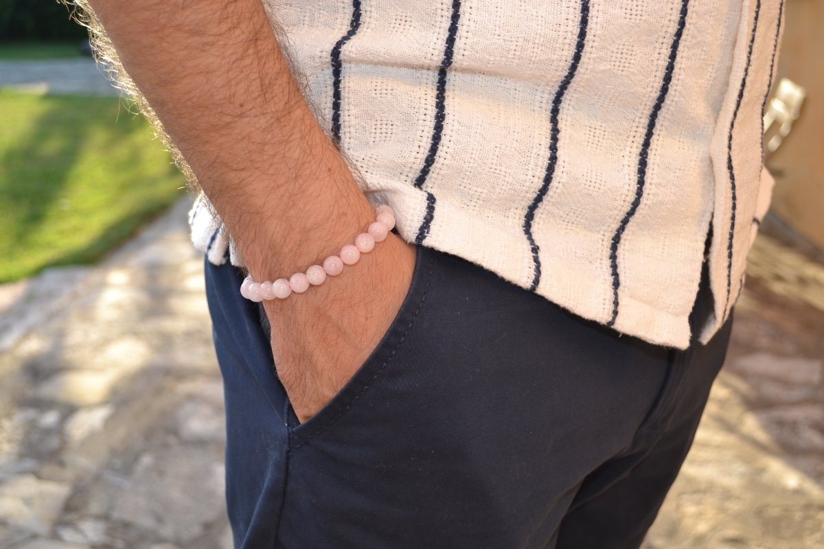 Bracelet Quartz Rose en pierre naturelle porté sur un poignet d'un homme au niveau de la hanche. perle de diamètre 5-6mm