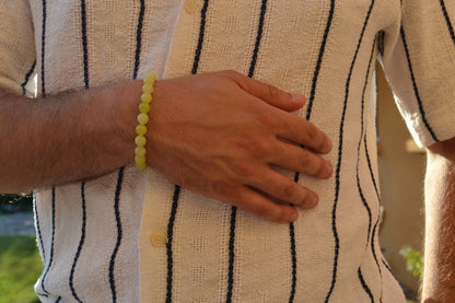 Bracelet Jade Citron en pierre naturelle porté sur un poignet d'un homme au niveau du ventre. perle de diamètre 7-8mm